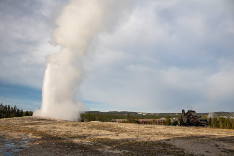 Old Faithful eruption in morning light with Old Faithful Inn, Yellowstone National Park